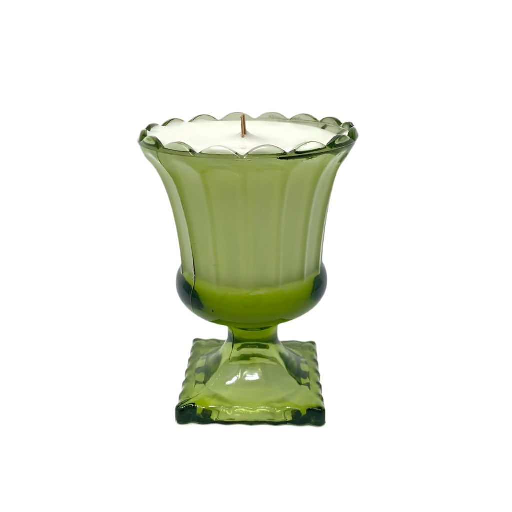 Green glass candle holder with a white candle inside on a white background