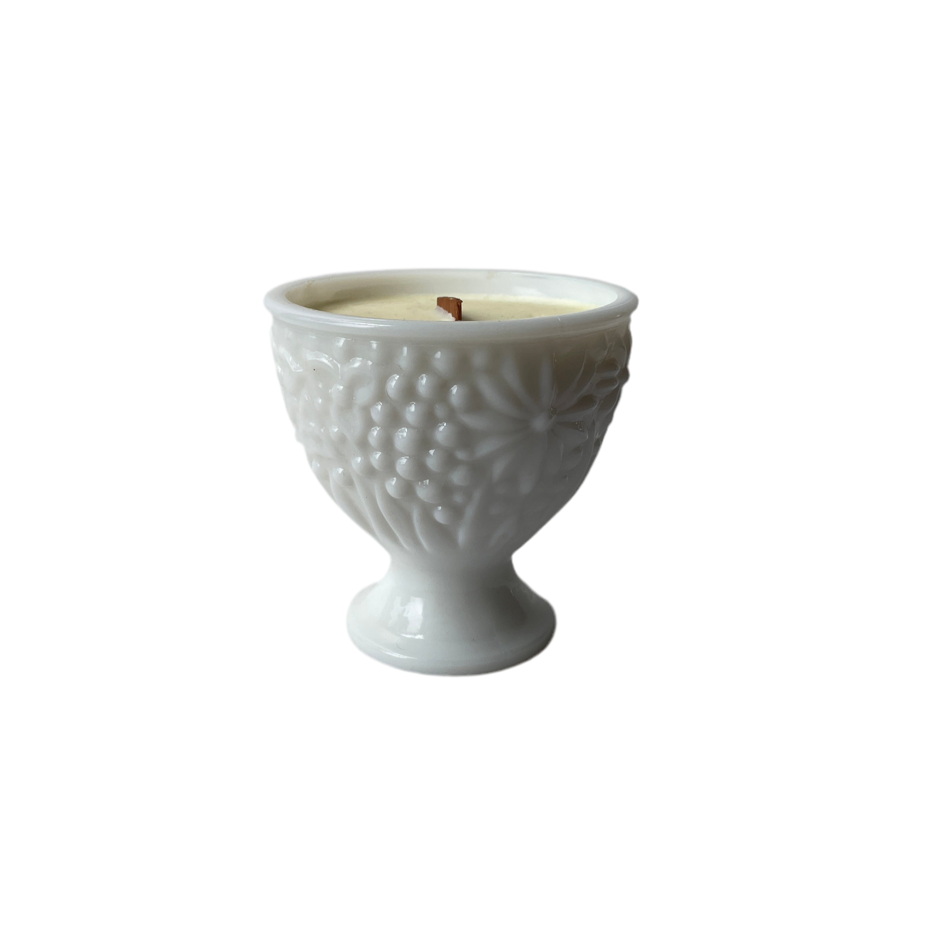 White textured candle holder with a lit candle on a white background